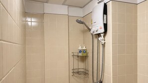Un pequeño espacio de ducha con azulejos, un cabezal de ducha manual y un panel de control en la pared.
