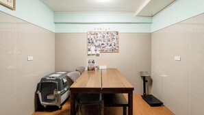 Una habitación con una mesa de madera, un transportín para mascotas, un cartel y un enchufe de pared.