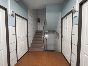 A hallway with a staircase, white doors, and a fire extinguisher. - Homies Ratchada Hotel (Bangkok)