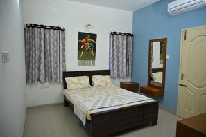 A bedroom with a bed, curtains, a wall-mounted mirror, and an air conditioning unit.