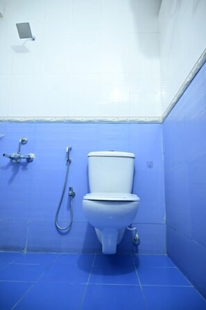 A bathroom with a toilet, a shower, and a hand dryer.