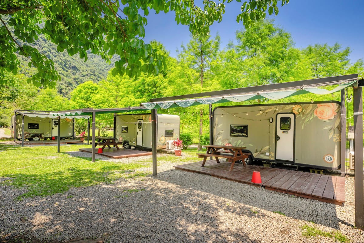 A row of RVs with picnic tables and a gravel ground.