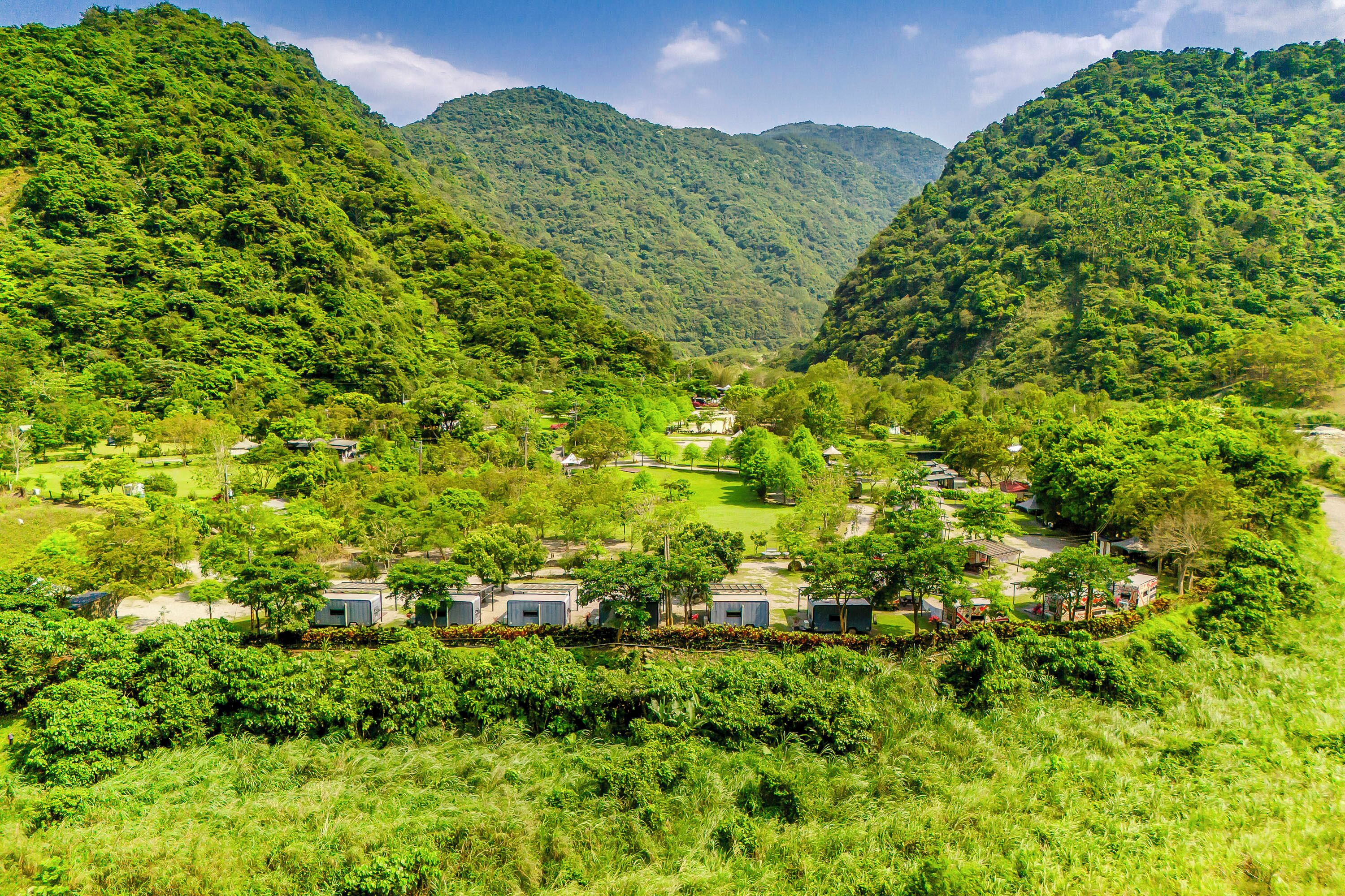 A mountainous landscape with a small village featuring several cabins and a clear view of the valley below.