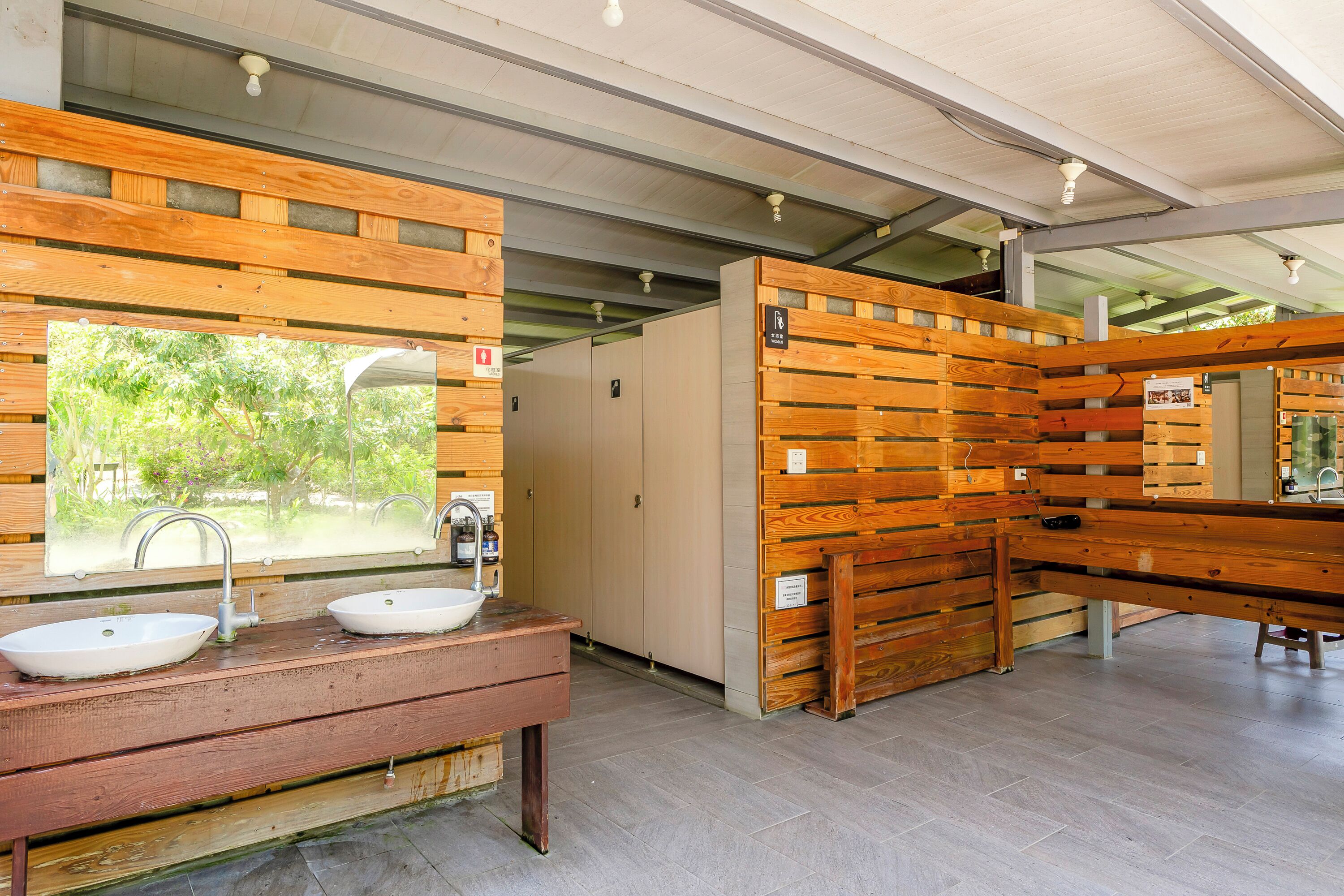 A modern bathroom with wooden accents, two sinks, and a bench.