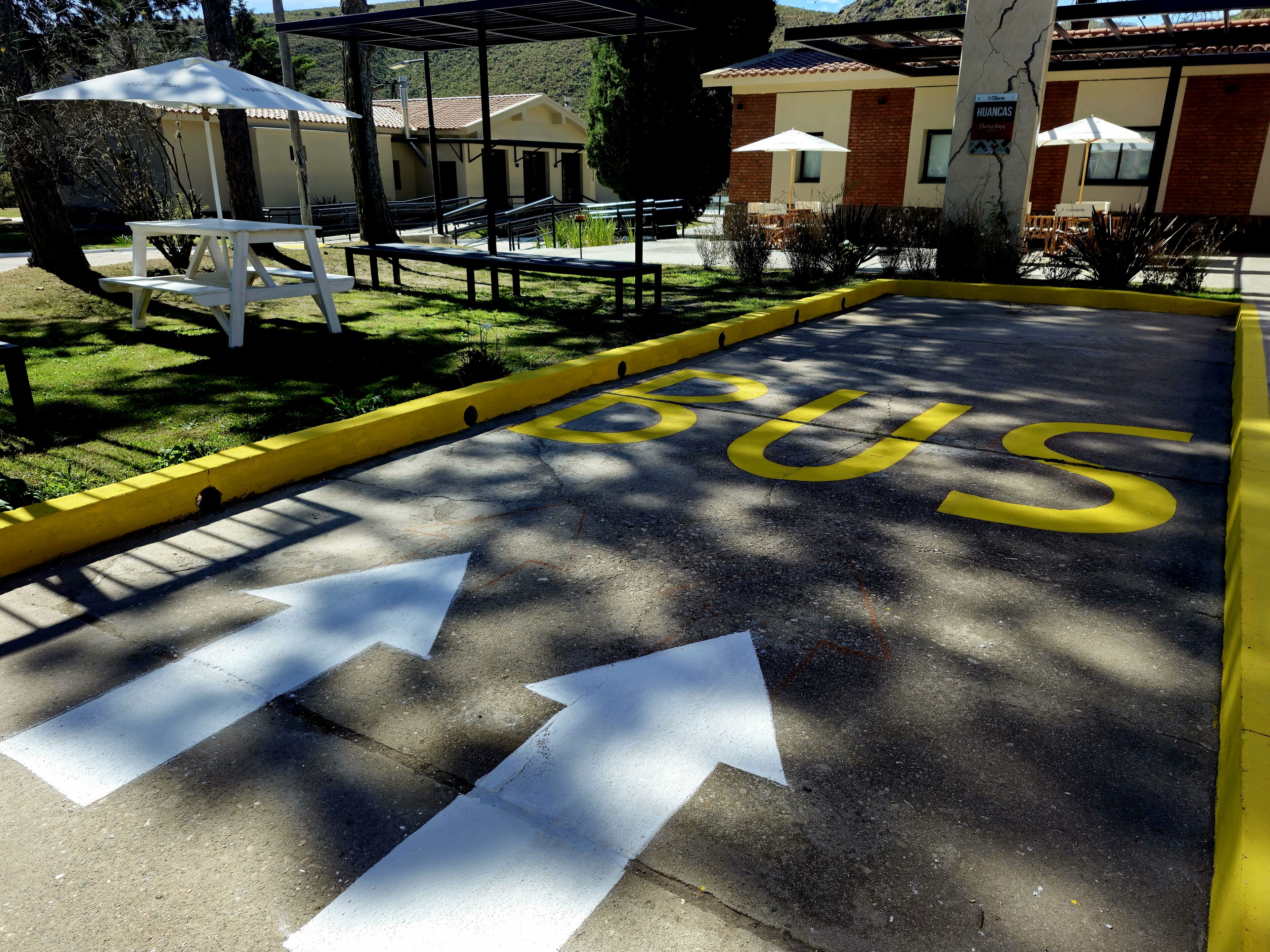 A parking area with a bus stop sign and directional arrows.