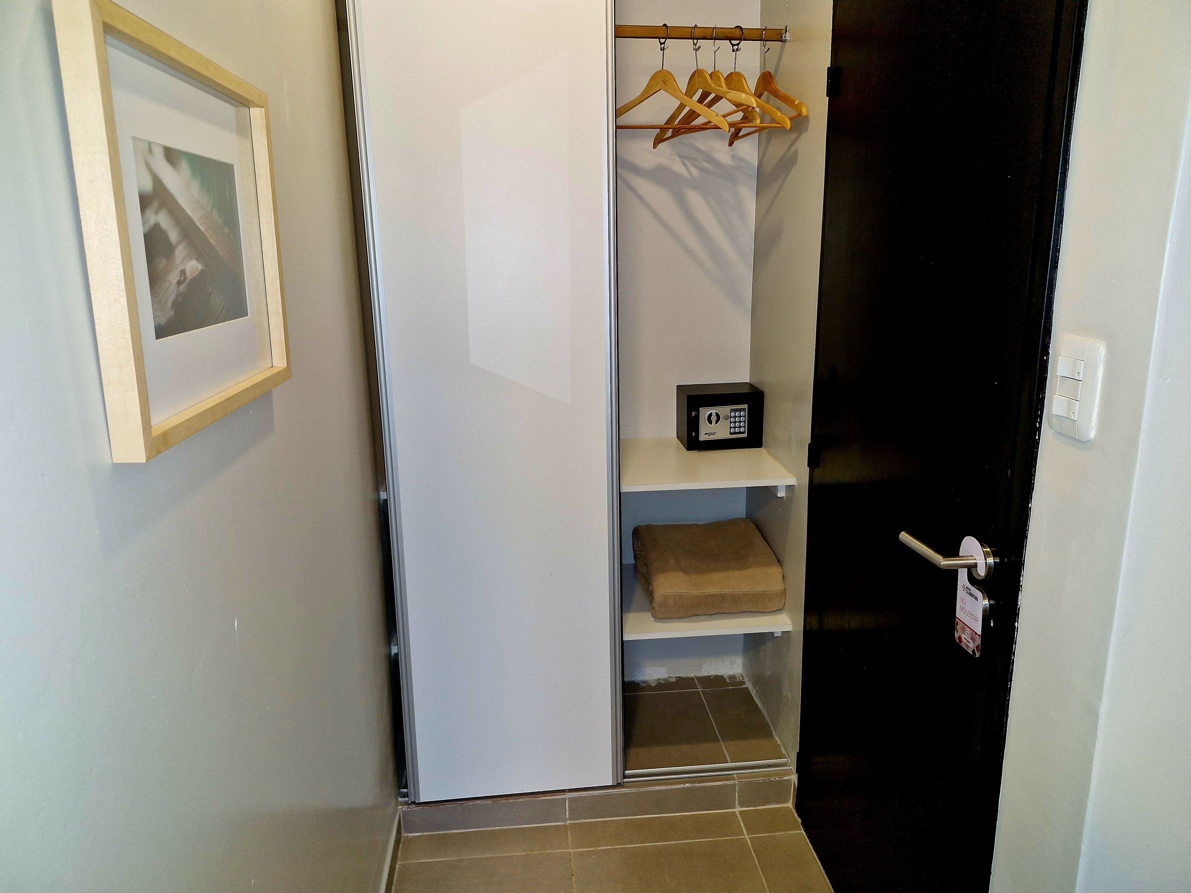 Un armario vestidor con una percha, un estante con una caja negra y un cuadro en la pared.