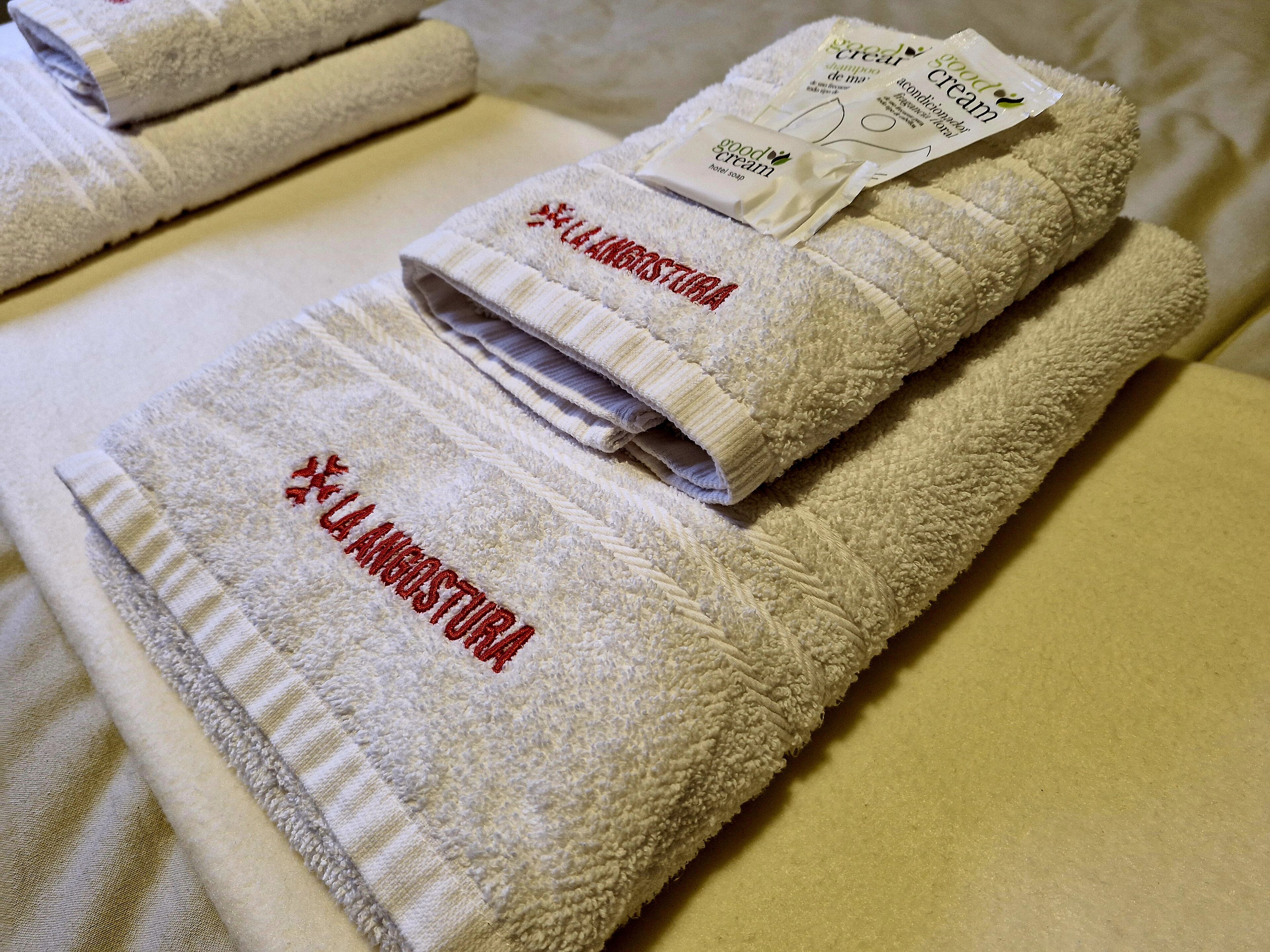 Una tovallola ben arrugada amb text brodat i una etiqueta que indica que és sabó d'hotel.