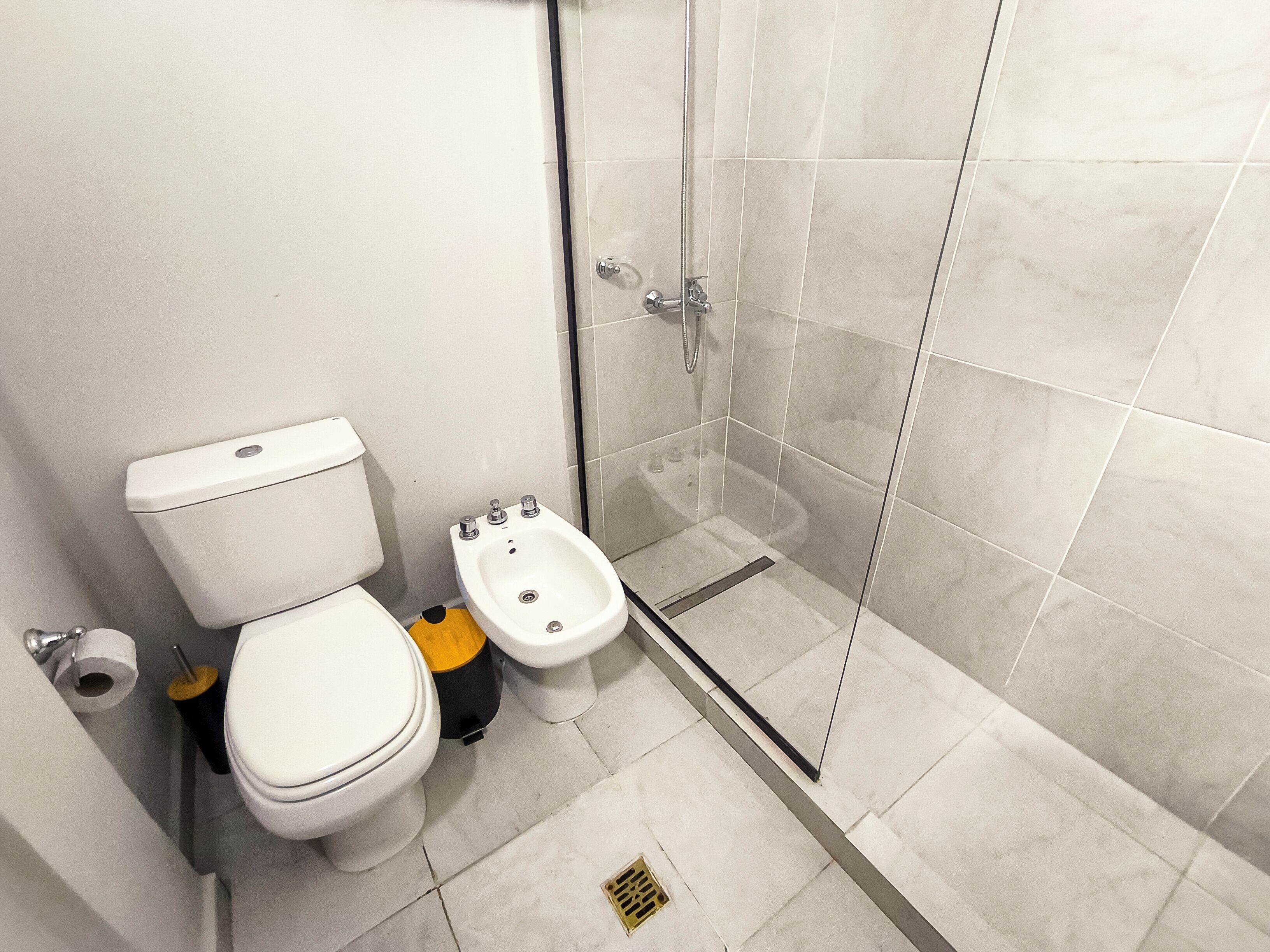 Un baño moderno con inodoro, bidé y cabina de ducha de vidrio.
