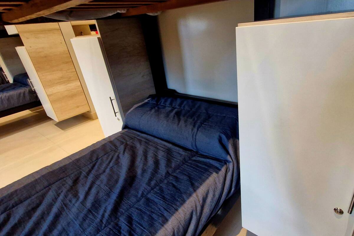 Un intérieur de camping-car compact comprenant un lit superposé, une petite kitchenette et un meuble blanc.