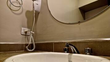 Un baño con un lavamanos blanco, un espejo y un secador de pelo conectado a la pared.