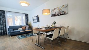 Un salon moderne avec un canapé, une table à manger, des chaises et un tableau accroché au mur.
