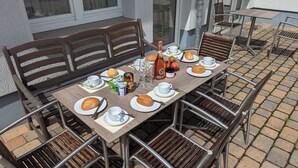 Une table à manger dressée avec des assiettes, du pain, du vin et des condiments.