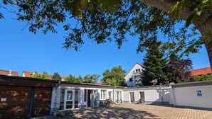 Une cour intérieure avec un bâtiment doté de grandes portes vitrées et d’un espace de repos abrité.