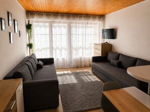 A modern living room with a sofa set, a dining table, and a TV on a wooden cabinet. - Nice studio 4 pers near the slopes (Orcières)