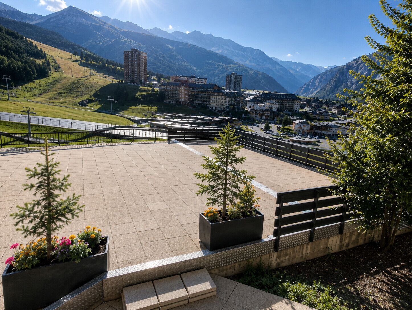 A spacious outdoor area with a paved surface, benches, and flower planters.