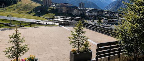 A spacious outdoor area with a paved surface, benches, and flower planters.