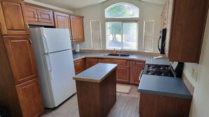 A kitchen with wooden cabinets, a white refrigerator, a sink, and a stove. - Desert Haven Resort Perfect for Active Couples Seeking Adventure (Jacumba Hot Springs)