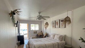 Une chambre à coucher avec un lit, un ventilateur de plafond, une fenêtre et un radiateur.