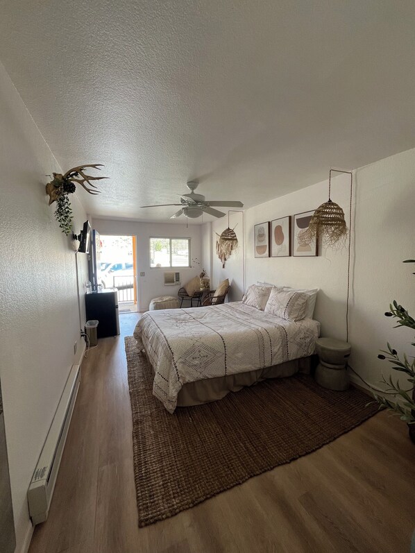 Una camera da letto con un letto, una ventola a soffitto, una finestra e un termosifone.