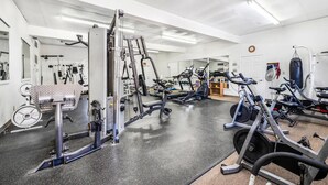 Une salle de sport équipée de divers appareils d’exercice, notamment des appareils de musculation, des tapis de course et des vélos d’appartement.