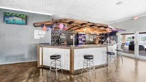 Un espace bar avec un plafond en bois, un téléviseur fixé au mur et une vue sur l’extérieur.