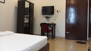 Una habitación de hotel con cama, escritorio con silla, televisor y armario.