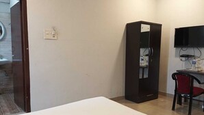 Una habitación de hotel con cama, escritorio, silla, armario y televisor.