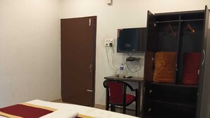Una habitación de hotel con cama, escritorio, silla, armario y televisor.