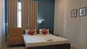 Un dormitorio con cama, una silla y un ventanal con cortinas.