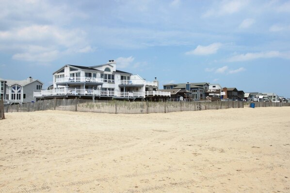 A beachfront property with multiple-story houses, a wooden fence, and a sandy beach. - Peaceful, 2 BD, 2 BA Condo w/ Water Views, Pool and Free Activities Including Golf! (Ocean View)