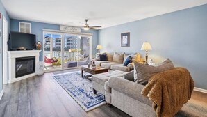 A living room with a fireplace, a television, a sofa, and a coffee table. - Peaceful, 2 BD, 2 BA Condo w/ Water Views, Pool and Free Activities Including Golf! (Ocean View)