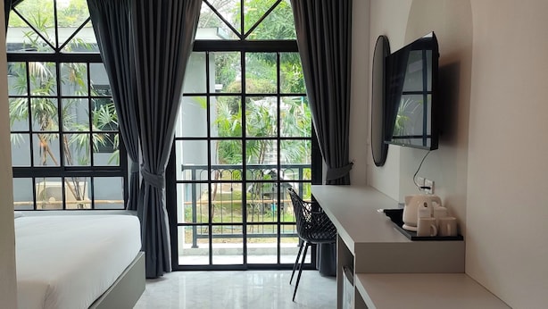 A modern hotel room with a bed, desk, chair, TV, and large windows with curtains. - The Target Hotel chaingrai  (Chiang Rai)