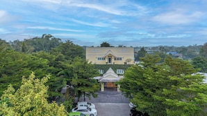A large, two-story building with a symmetrical facade, surrounded by lush greenery. - The Target Hotel chaingrai  (Chiang Rai)