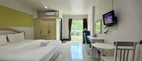 Habitación de hotel con cama, escritorio, silla, televisor y ventana con cortinas.