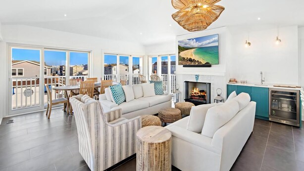 A spacious living room with a large sofa, a fireplace, and a view of the beach.