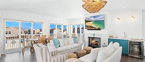 Amplia sala de estar con un sofá grande, una chimenea y vista a la playa.