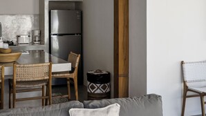 Une cuisine moderne avec un réfrigérateur en acier inoxydable, des chaises en bois et un luminaire suspendu en osier.