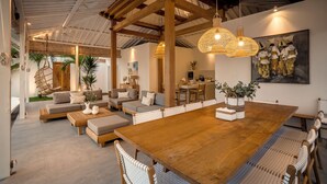 Un vaste espace de vie comprenant une grande table à manger en bois, des sièges confortables et un ventilateur de plafond.