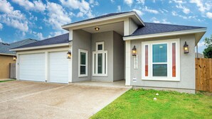 Une maison à deux étages avec un garage, une porte d’entrée et deux fenêtres équipées de volets.