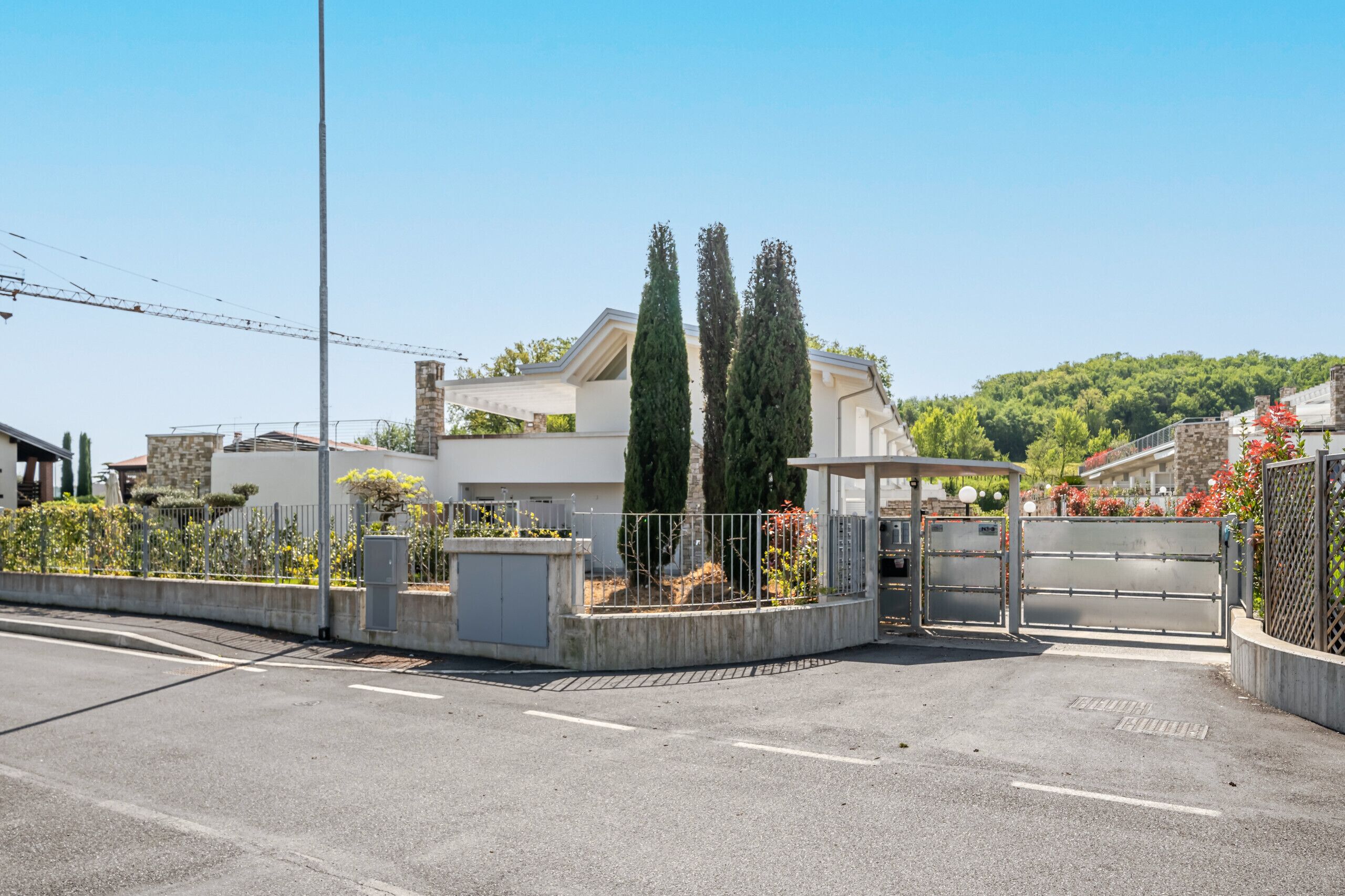 Un lotissement résidentiel fermé, avec une maison moderne, un ciel dégagé et un paysage vallonné en arrière-plan.