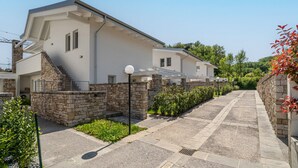A modern two-story house with a stone facade, a covered porch, and a well-maintained garden.