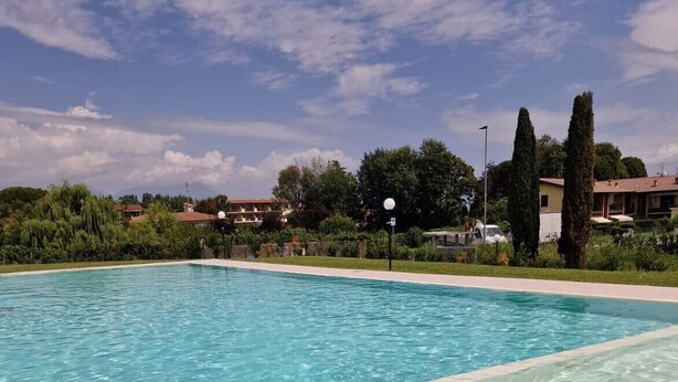 A clear swimming pool with a view of surrounding greenery and buildings.
