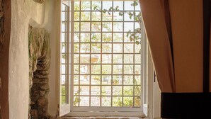 Una habitación rústica con pared de piedra, una ventana de cuadrícula y un banco.