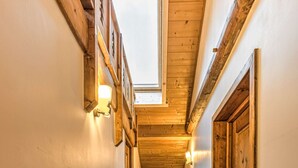 Ein schmaler Korridor mit Holzdielen und -wänden, einem Oberlicht und einer Heizung.