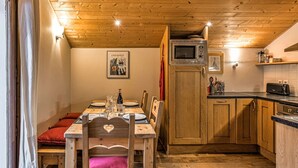 Ein gemütlicher Essbereich aus Holz mit einem Tisch für vier Personen, einer Mikrowelle über der Arbeitsplatte und einer Küche mit Holzschränken.