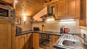 Eine Küche mit Holzausstattung, einer Edelstahl-Mikrowelle, einem Toaster und einem Spülbecken.