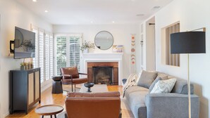 Un salon moderne avec une cheminée, des canapés en cuir, une table basse et un téléviseur fixé au mur.