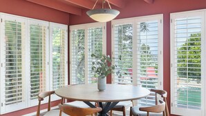Un coin repas avec une table ronde, six chaises et un vase avec une plante.