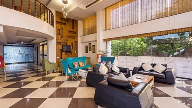 A spacious lobby with a checkered floor, a staircase, and a large window with a view of greenery.