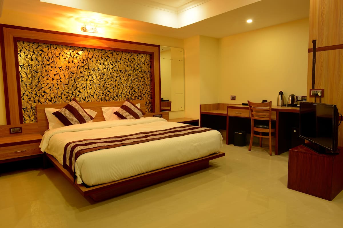 Quarto de hotel moderno com uma cama grande, uma escrivaninha e uma televisão.